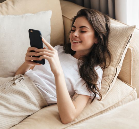 woman laying on the couch holding her phone