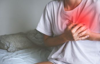 Woman holding chest because of acute heart pain or chest pain.