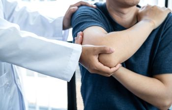 A man with shoulder pain at a doctor's appointment.