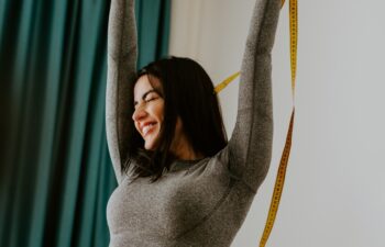 happy Woman Measuring body With Tape after weight loss fitness workout. Beautiful smiling woman measuring butt in front of mirror in living room after fitness marathon